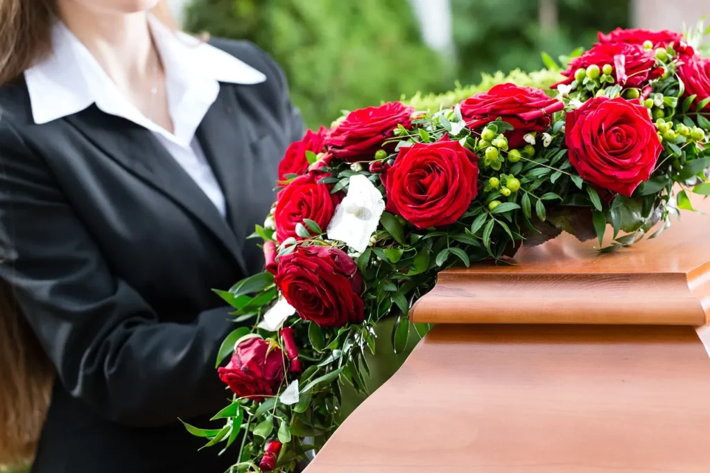 Chapeau de recueilllement en roses rouges posé sur un cercueil en bois élégant.