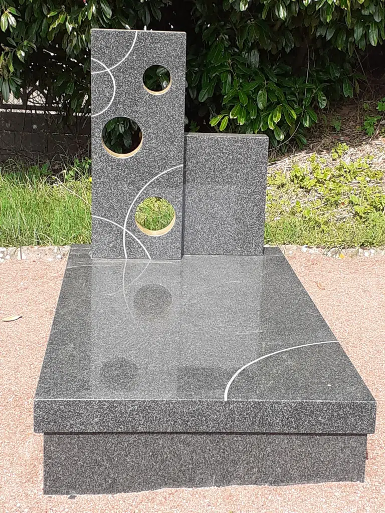 Monument funéraire contemporain en granit sombre avec motifs géométriques.