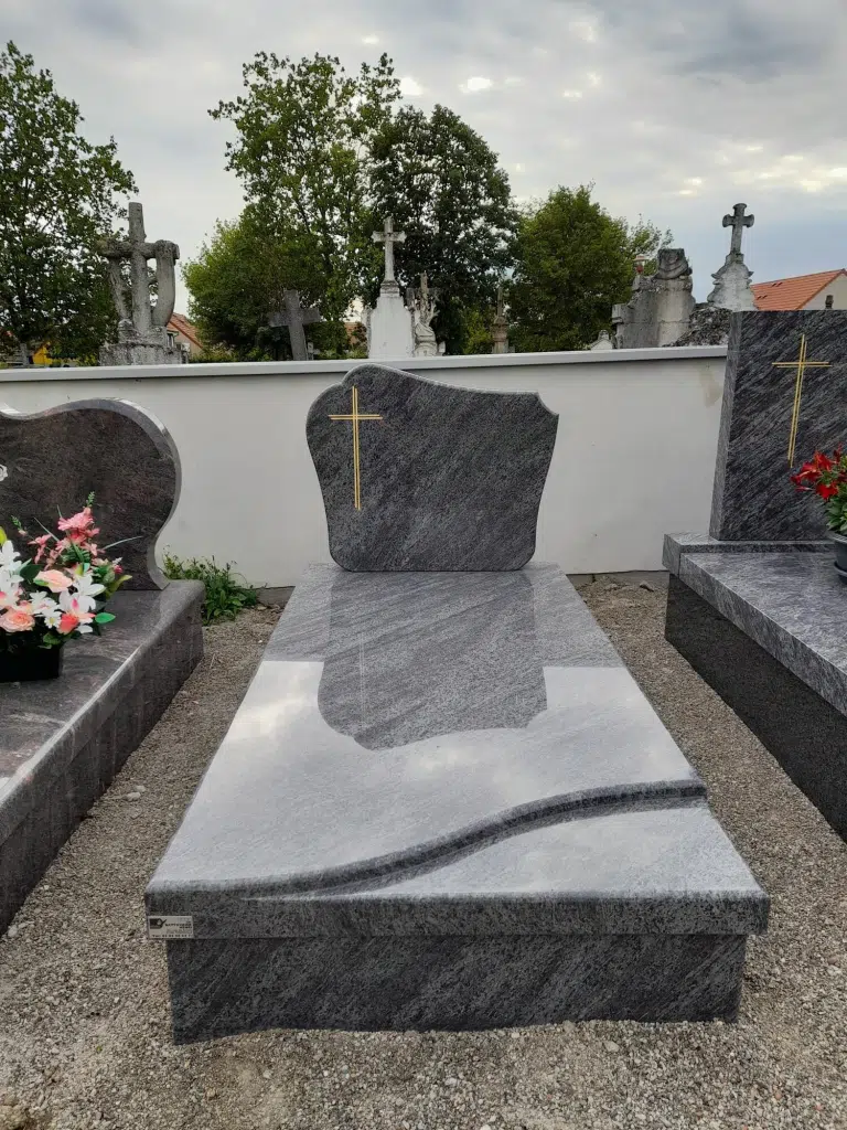 Pierre tombale en granit gris avec gravure dorée d'une croix chrétienne.