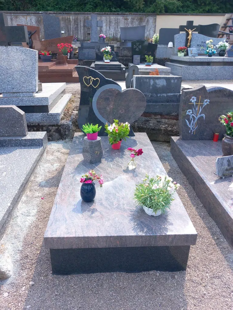 Monument funéraire en granit personnalisé en forme de cœur avec fleurs.