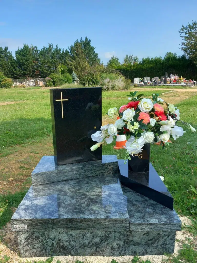 Monument cinéraire contemporain en granit sombre orné de fleurs colorées.