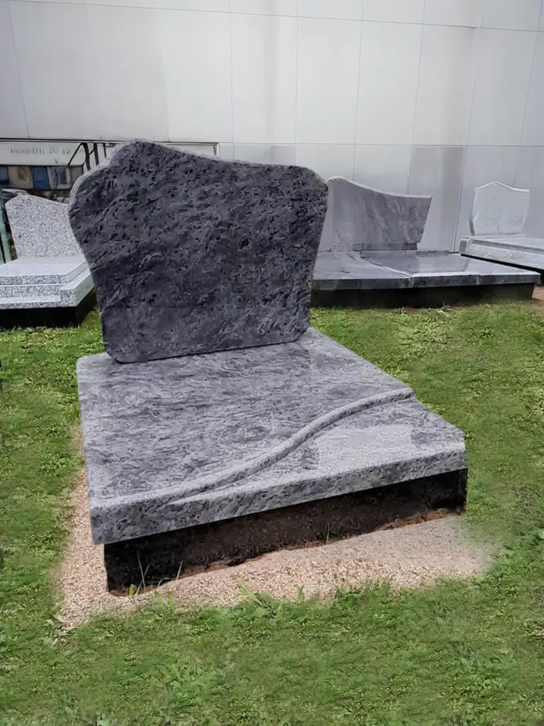 Petit monument cinéraire en granit bleu nuit avec stèle voutée.